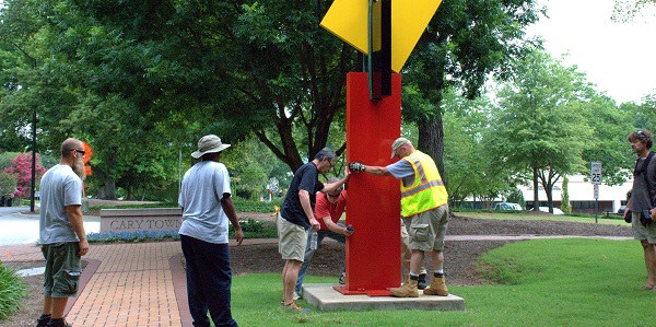 Town officials and CVA members help artist Ray Katz place his sculpture in front of Cary Town Hall.